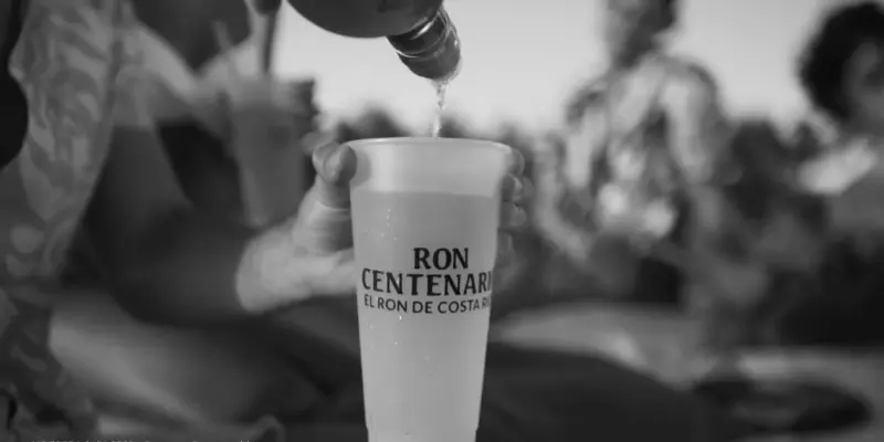 Un vaso de Ron Centenario siendo servido en la playa y con amigos
